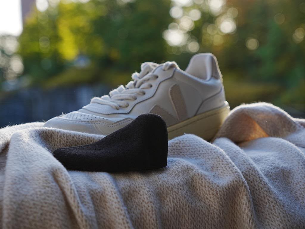 Kahyve shoe tree resting beside a sneaker outdoors